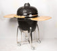 Black ceramic kamado-style BBQ with dome lid and steel frame on wheels view 2